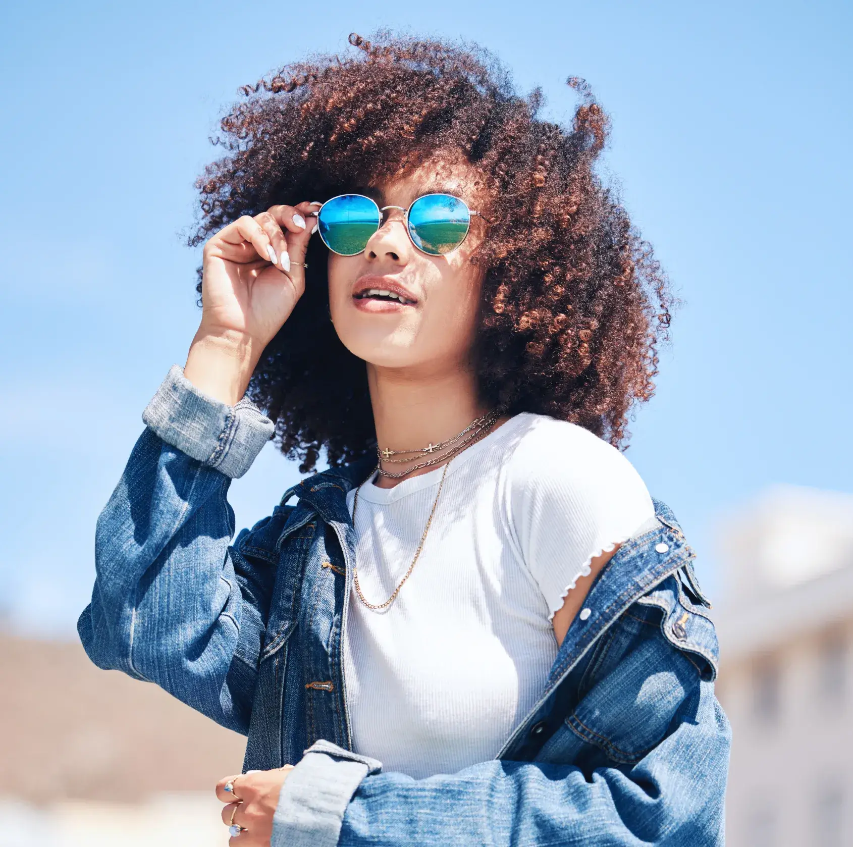 A woman wearing sunglasses and a denim jacket.