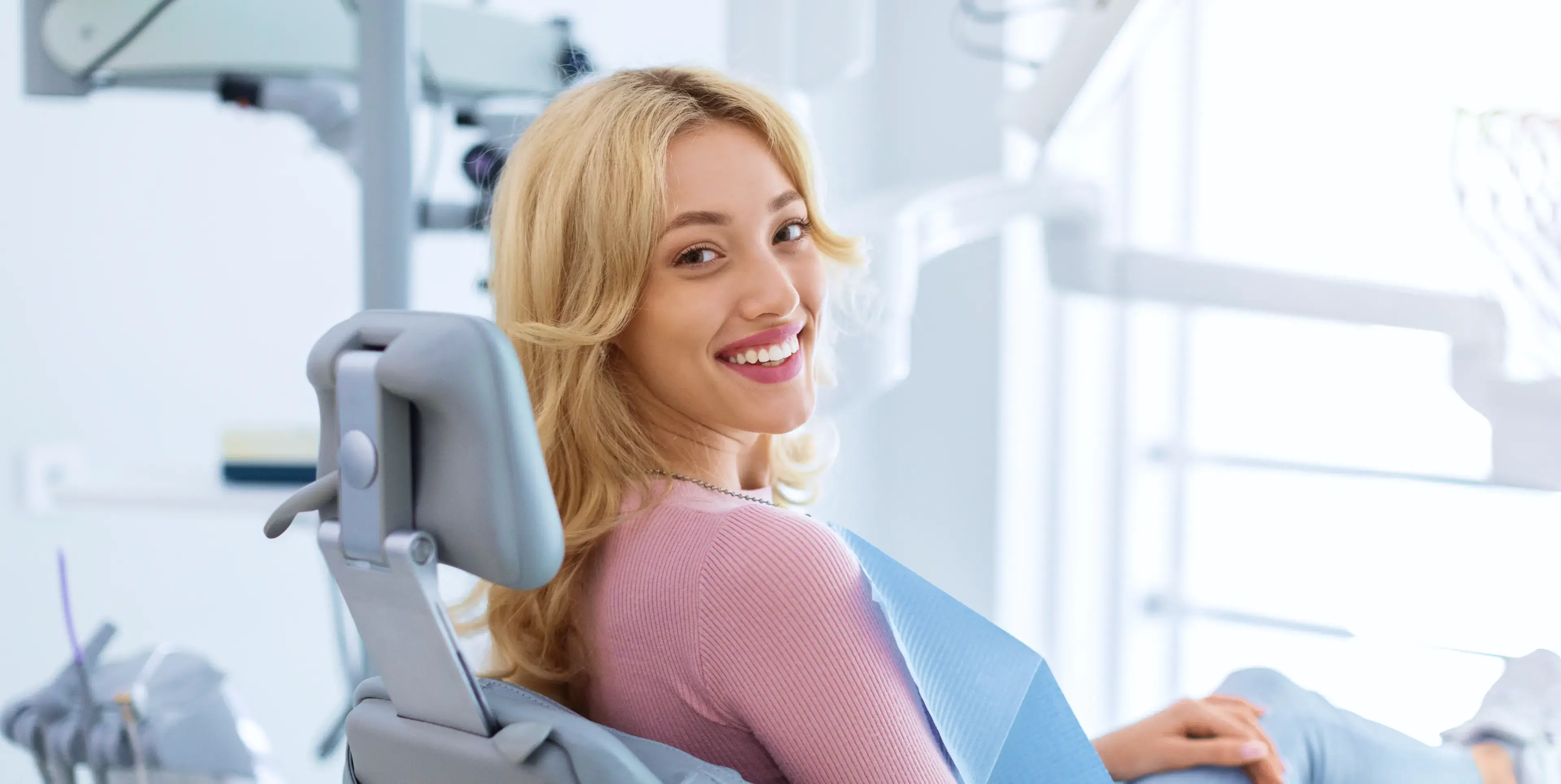 A woman sitting in a dental chair smiling.