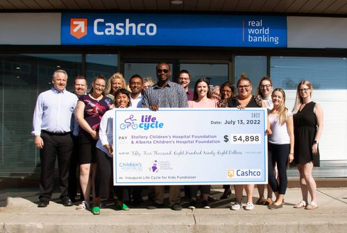 Cashco Financial team smiling in a group photo, holding a giant cheque for life cycle.