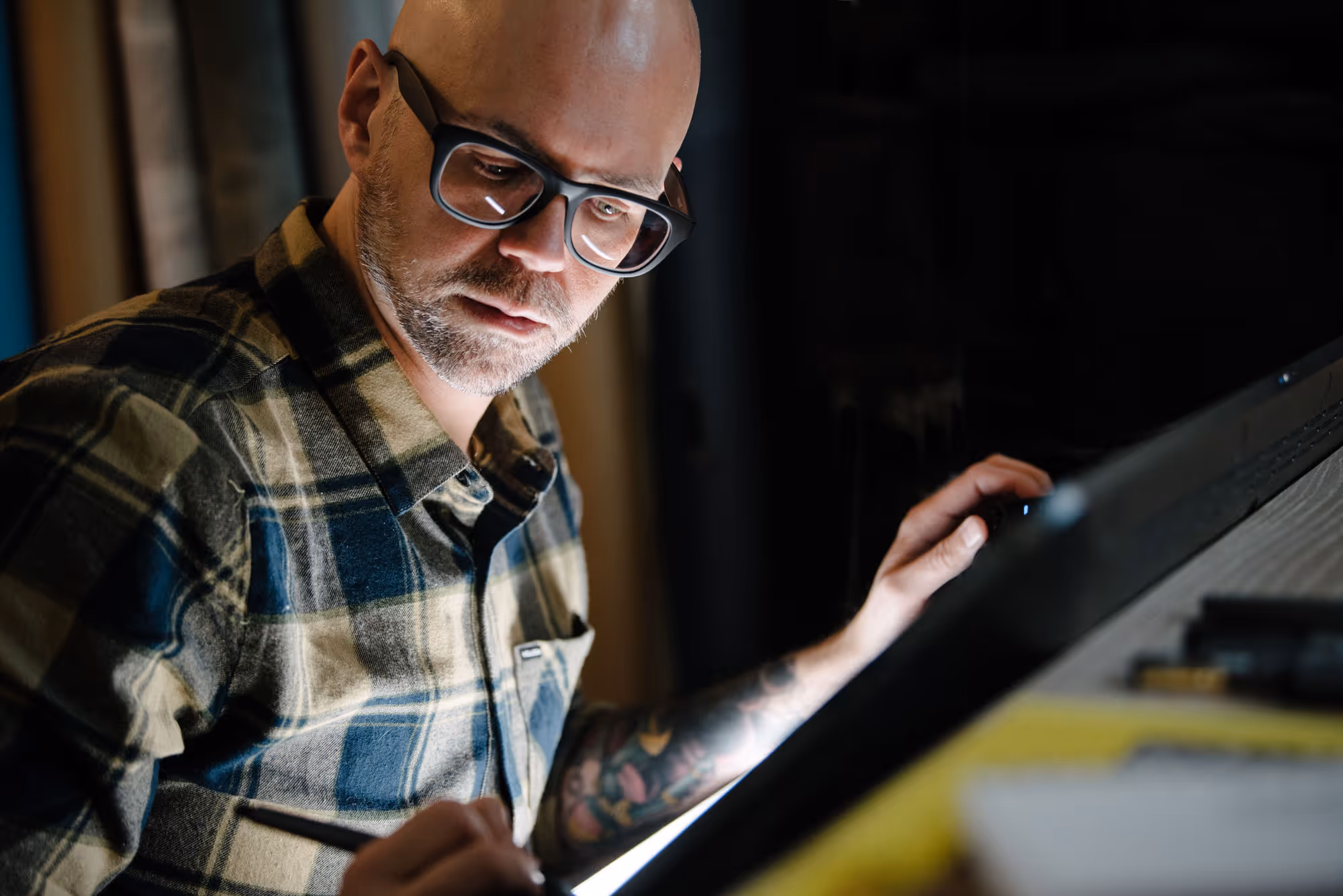 Man with glasses working on digital tablet.