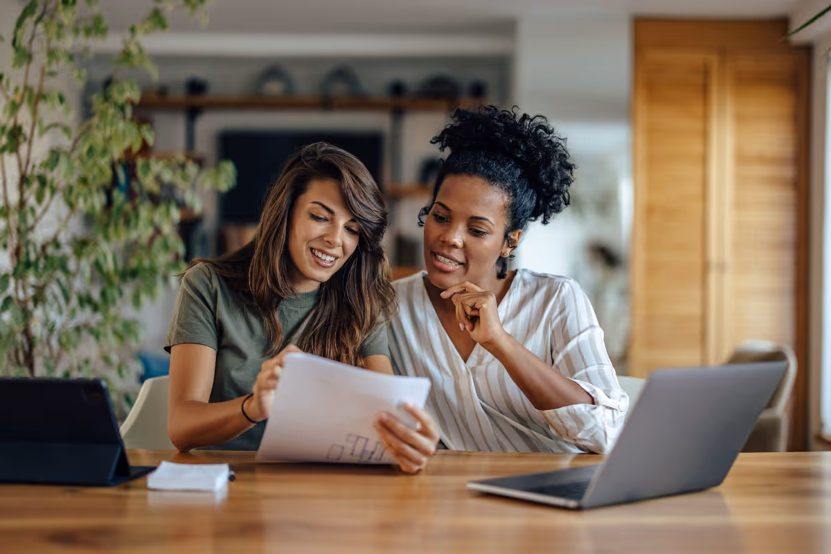 Two female product consultants collaborating on client project strategy with laptop and documents