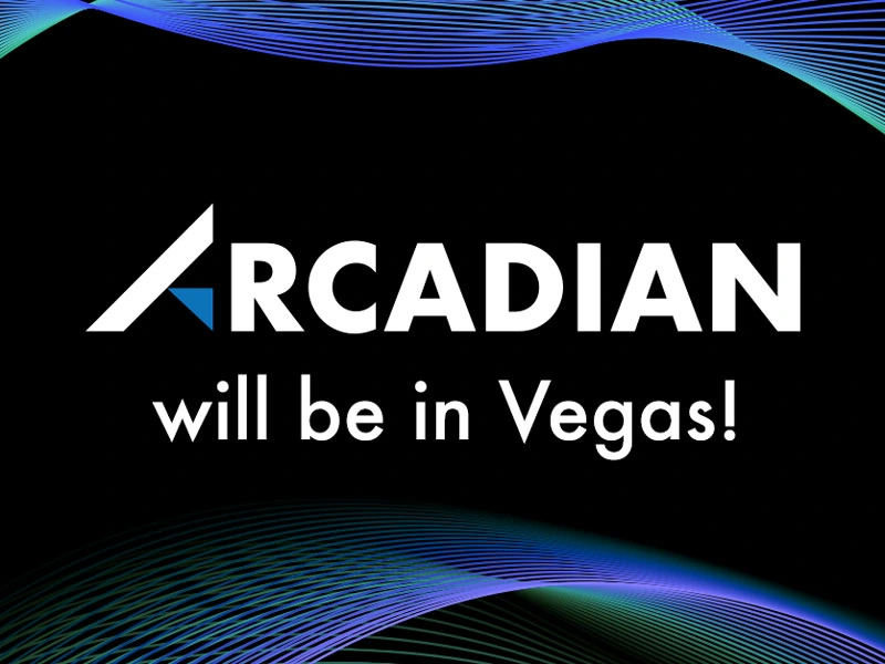 Promotional graphic with the Arcadian logo and the text 'Arcadian will be in Vegas!' displayed on a black background. Blue and green digital wave patterns accent the top and bottom edges, creating a dynamic and modern tech-inspired design.