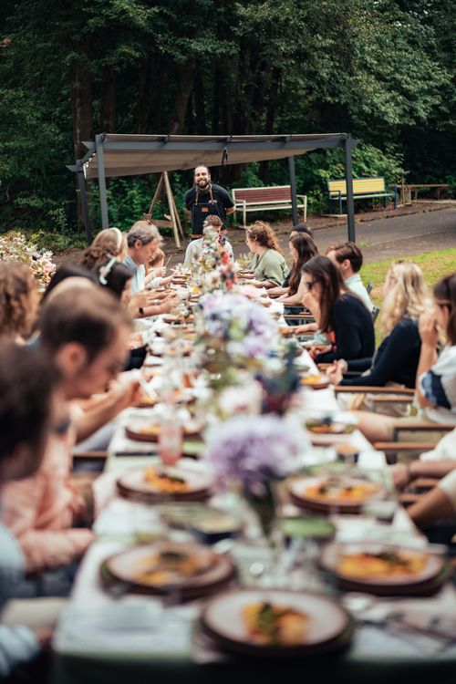 event catering eine lange tafel mit leckerem essen vollen tellern und gläsern und glücklichen gesichtern