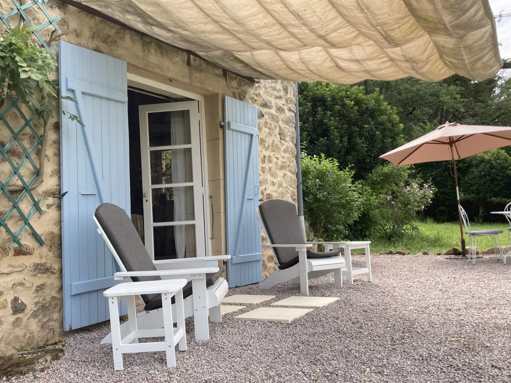Foto van de zijkant van het terras, twee ligstoelen voor de opengeklapte deuren.