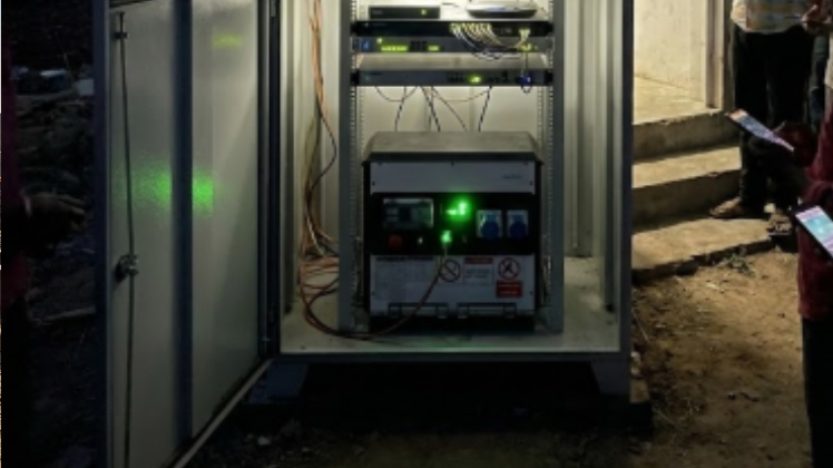 Person pushing a portable generator on a cart at a construction site during sunset.