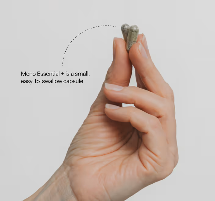 The image shows a hand holding a small, translucent capsule labeled "Meno Essential +," with the text indicating it is a small, easy-to-swallow capsule.