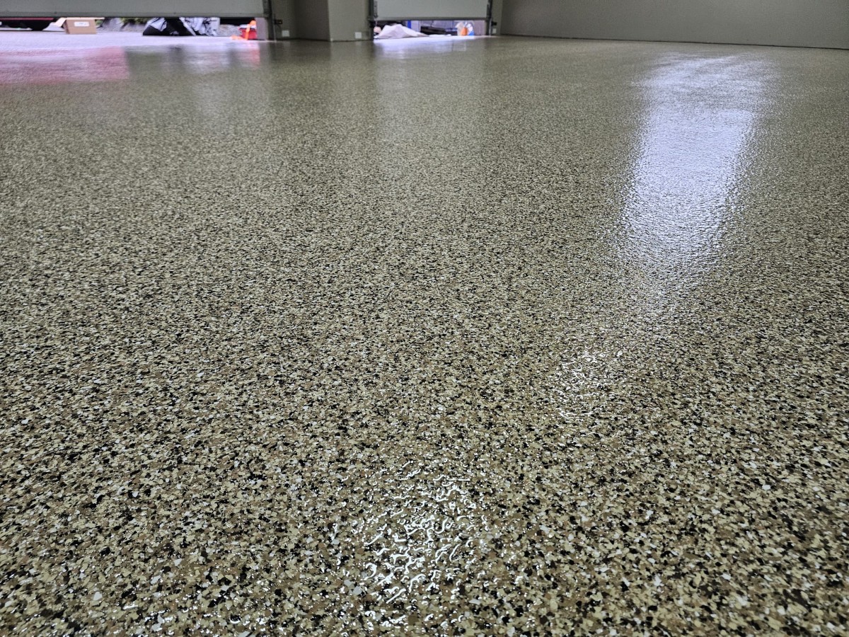 Close-up of a glossy tan and black flake epoxy garage floor