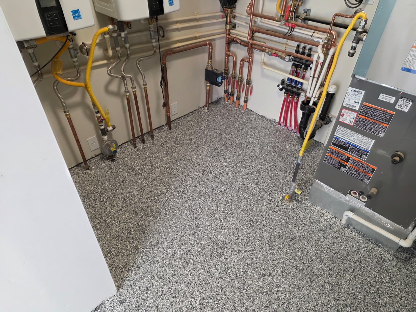 Gray flake epoxy floor fitted around the water heaters and furnace in a mechanical room