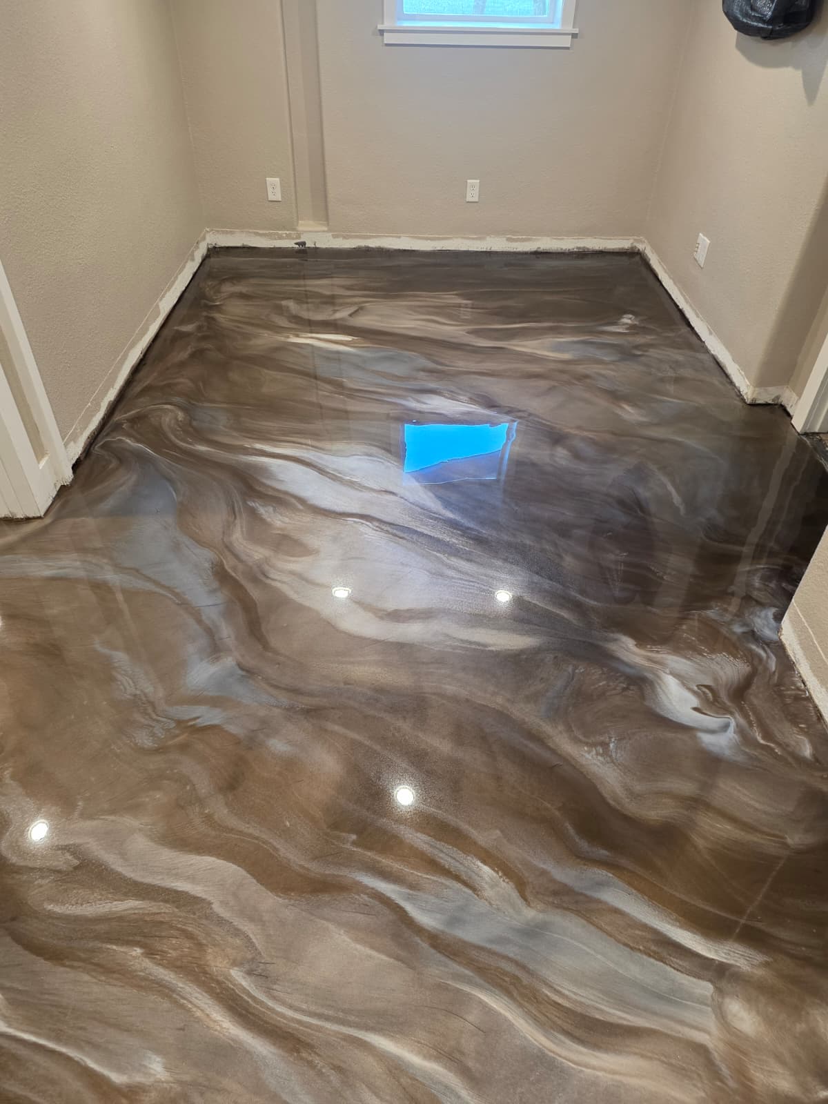 Bronze and silver metallic epoxy floor in a room with a window