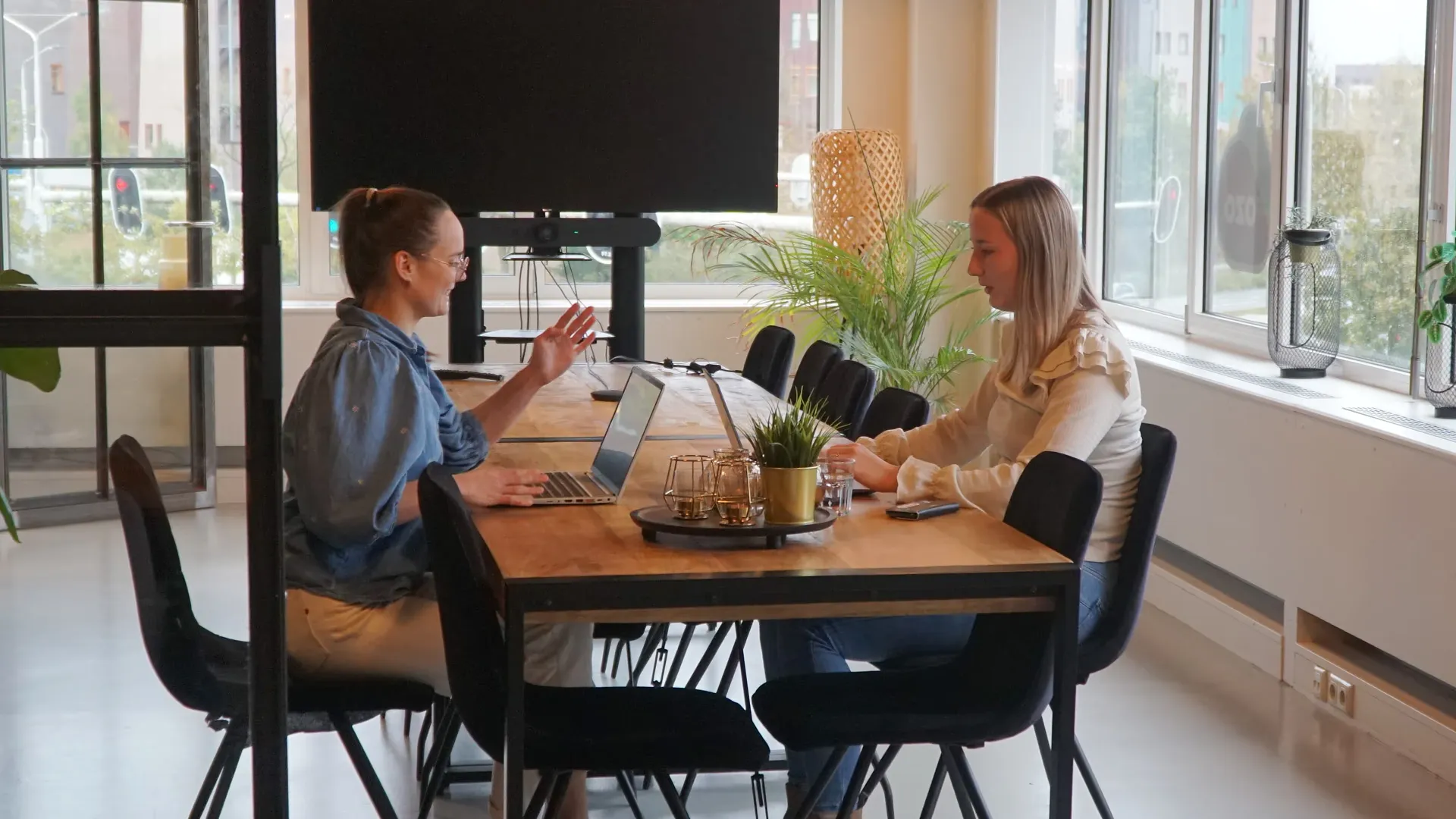 Twee zorgprofessionals in overleg aan een tafel met laptops