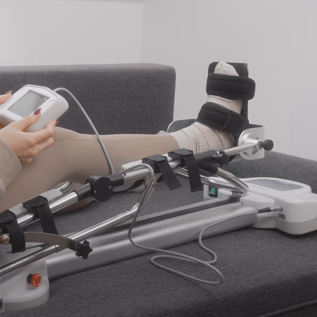 Osoba testująca szynę rehabilitacyjną OrtoFlex L2, trzymająca pilot z panelem sterowania. Ilustracja testów użyteczności UX aplikacji medycznej.