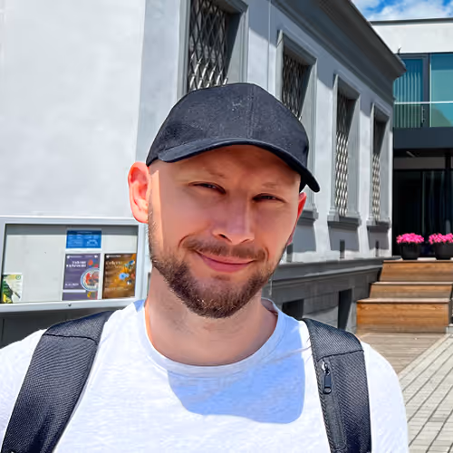 Portret Mateusza Mrozka na zewnątrz. Zdjęcie symbolizuje kreatywność i otwartość w dziedzinie grafiki i brandingu.