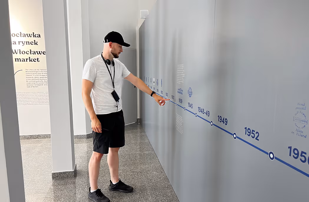 Mateusz Mrozek obsługujący gotową interaktywną oś czasu na wystawie Skarbiec Fajansu. Prezentacja funkcjonalności multimedialnej instalacji muzealnej.