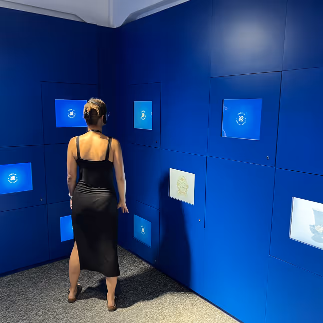 Zwiedzająca w pomieszczeniu Memory Room na wystawie Skarbiec Fajansu. Ilustracja interakcji z multimedialnymi instalacjami ekspozycji muzealnej.