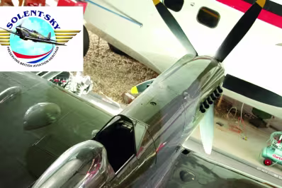 Top-down view of a vintage silver fighter aircraft model with open cockpit and visible propeller, displayed indoors.