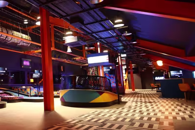 Interior of a brightly lit recreational arcade with colorful design elements and a checkered floor.
