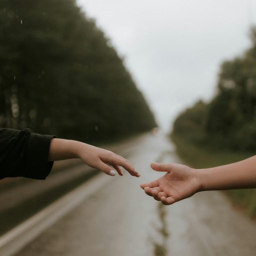 Hands reaching for each other outside on a rainy day - (heartbreak / lovesickness).