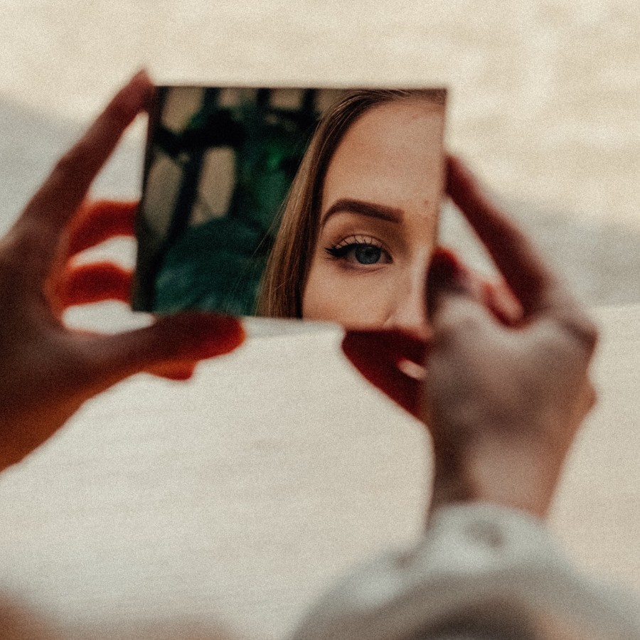 Woman with low self-esteem looking at herself in a mirror.