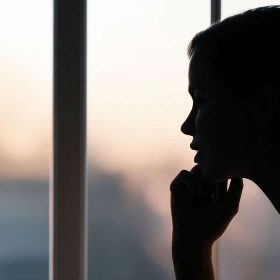 Silhouette of a person looking out the window during sunset. 