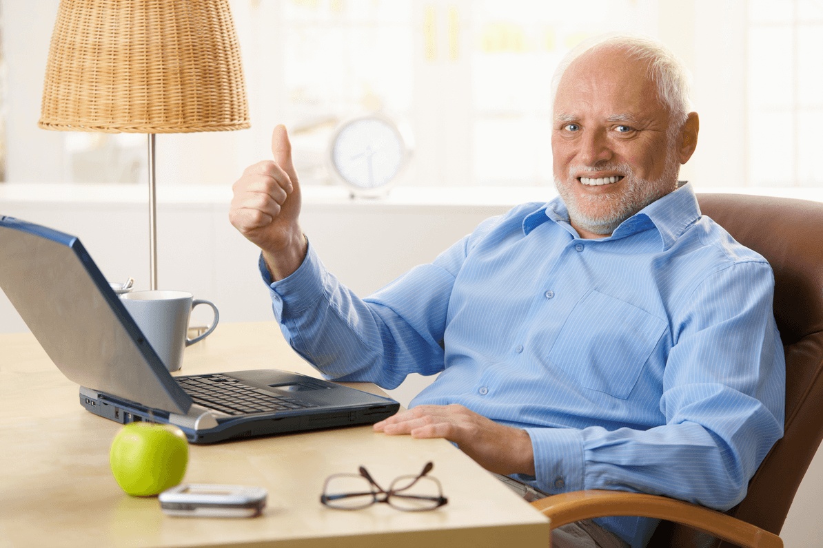 Senior man smiling while sitting at desk has healthy teeth after getting a dental implant for a missing tooth at the best implant dentist in Mountain View.