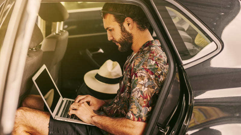 Person working on a laptop from a car representing remote work, flexibility and digital content creation Avant