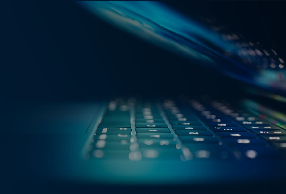 Nahaufnahme einer Laptop-Tastatur mit beleuchteten Tasten, unscharf im Vordergrund.