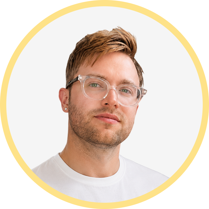 Portrait of a man with light brown hair, clear glasses, and a white shirt on a white background
