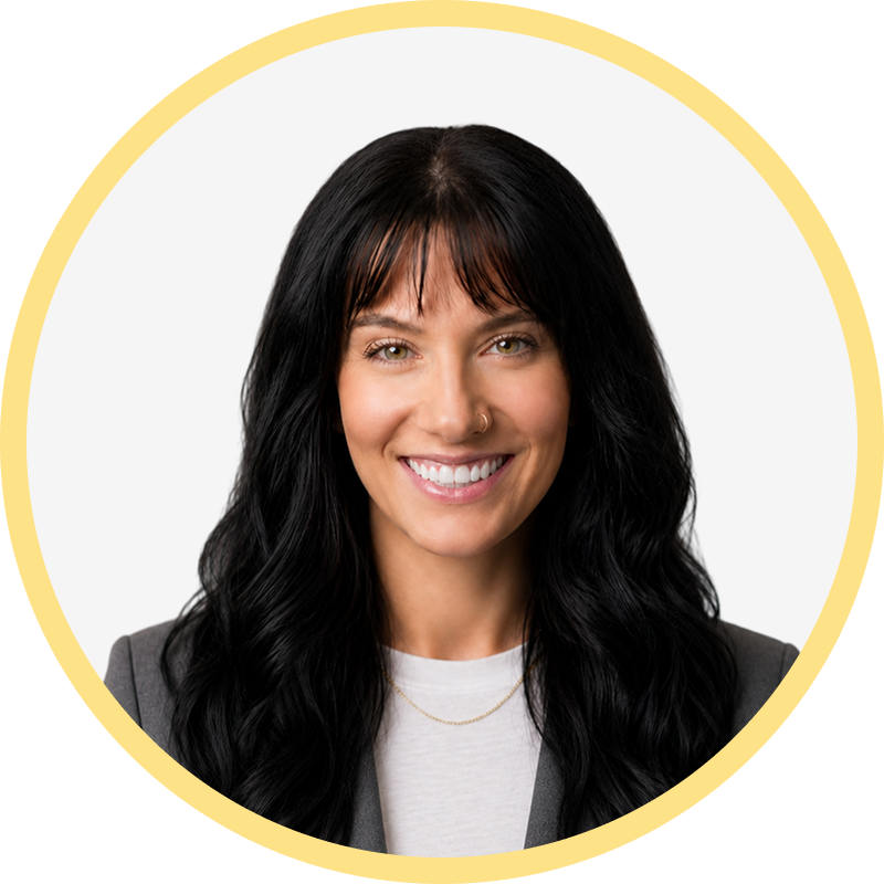 Smiling woman with long black hair, bangs, and a nose ring wearing a gray blazer and white shirt.