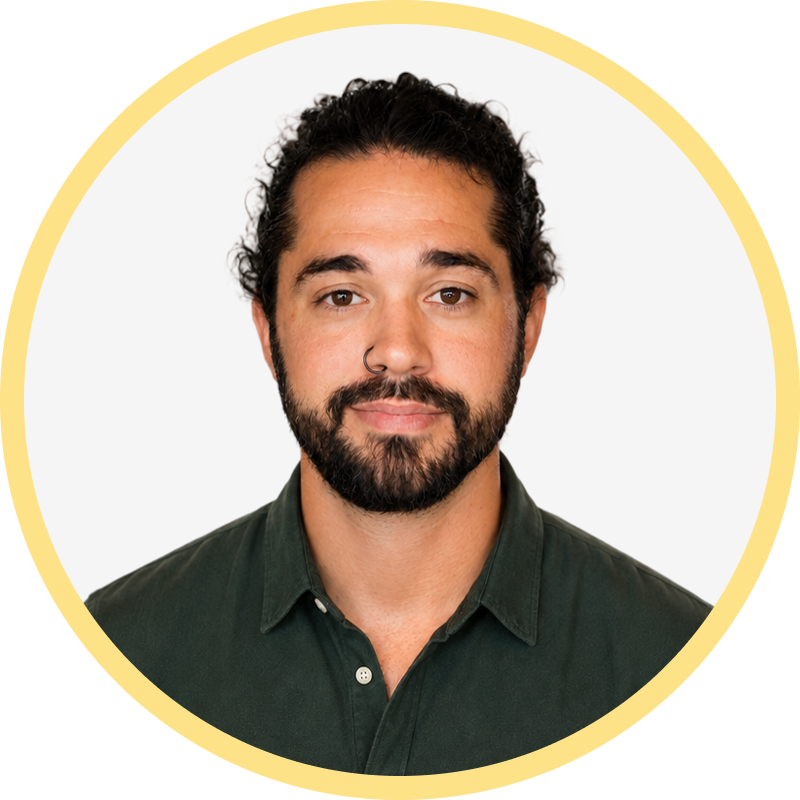 Man with curly dark hair, beard, nose ring, wearing a dark green buttoned shirt inside a yellow circular border.