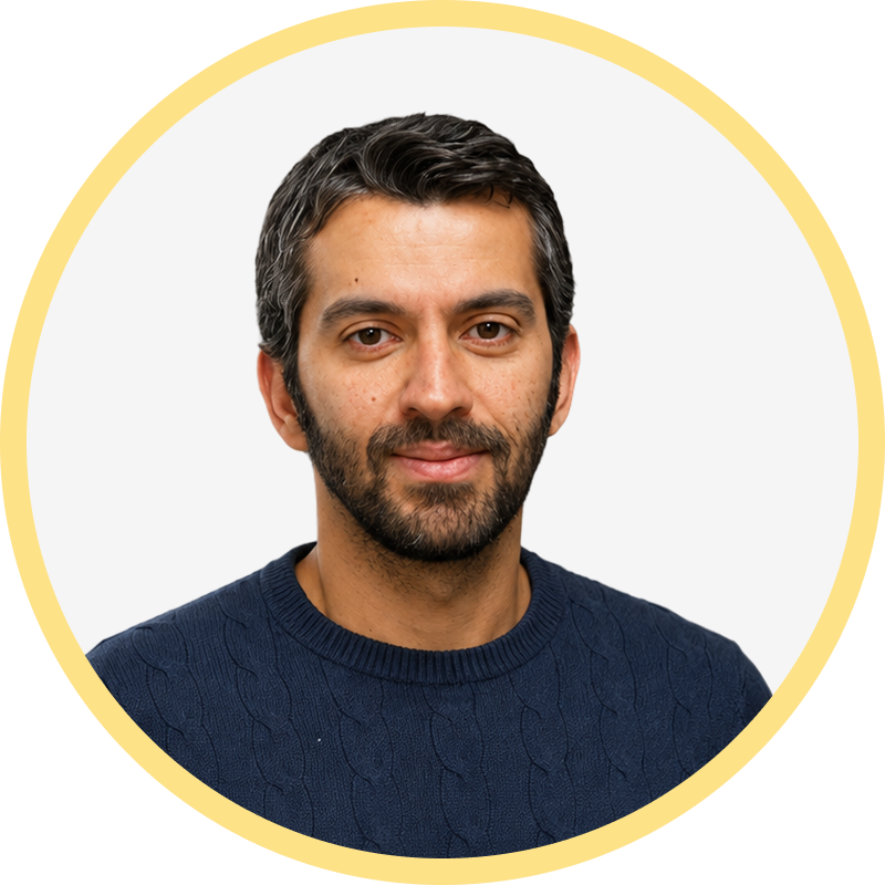 Headshot of a man with dark hair and beard wearing a navy blue cable-knit sweater.
