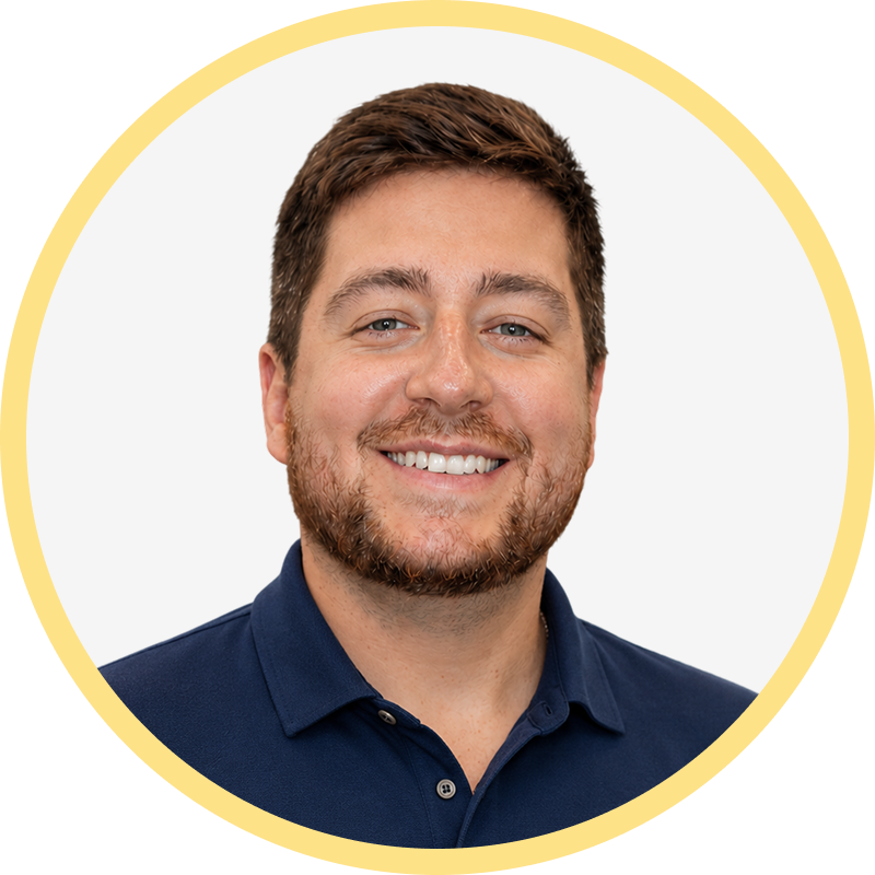 Smiling man with short brown hair and beard wearing a navy blue polo shirt.