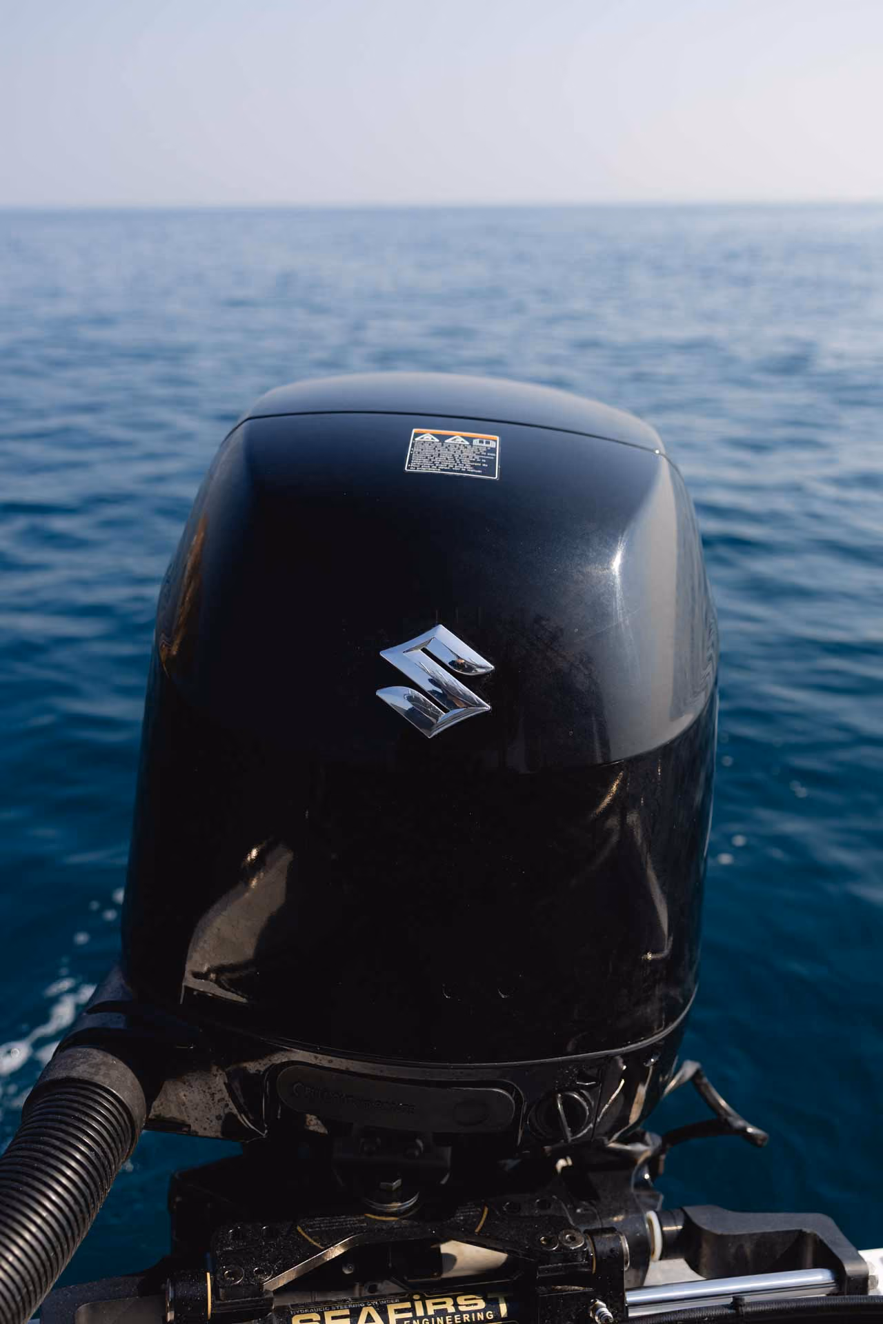 Close-up of a black Suzuki boat motor with the sea in the background.