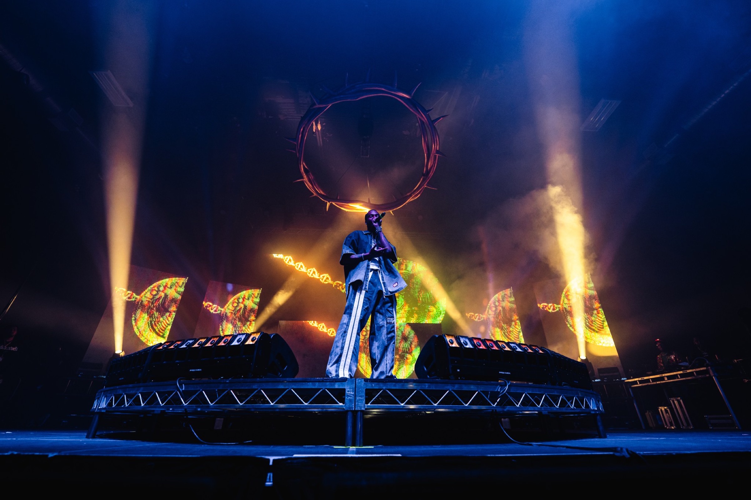 Solo performer on a riser in front of an amber LED wall, monitor wedges across the front edge