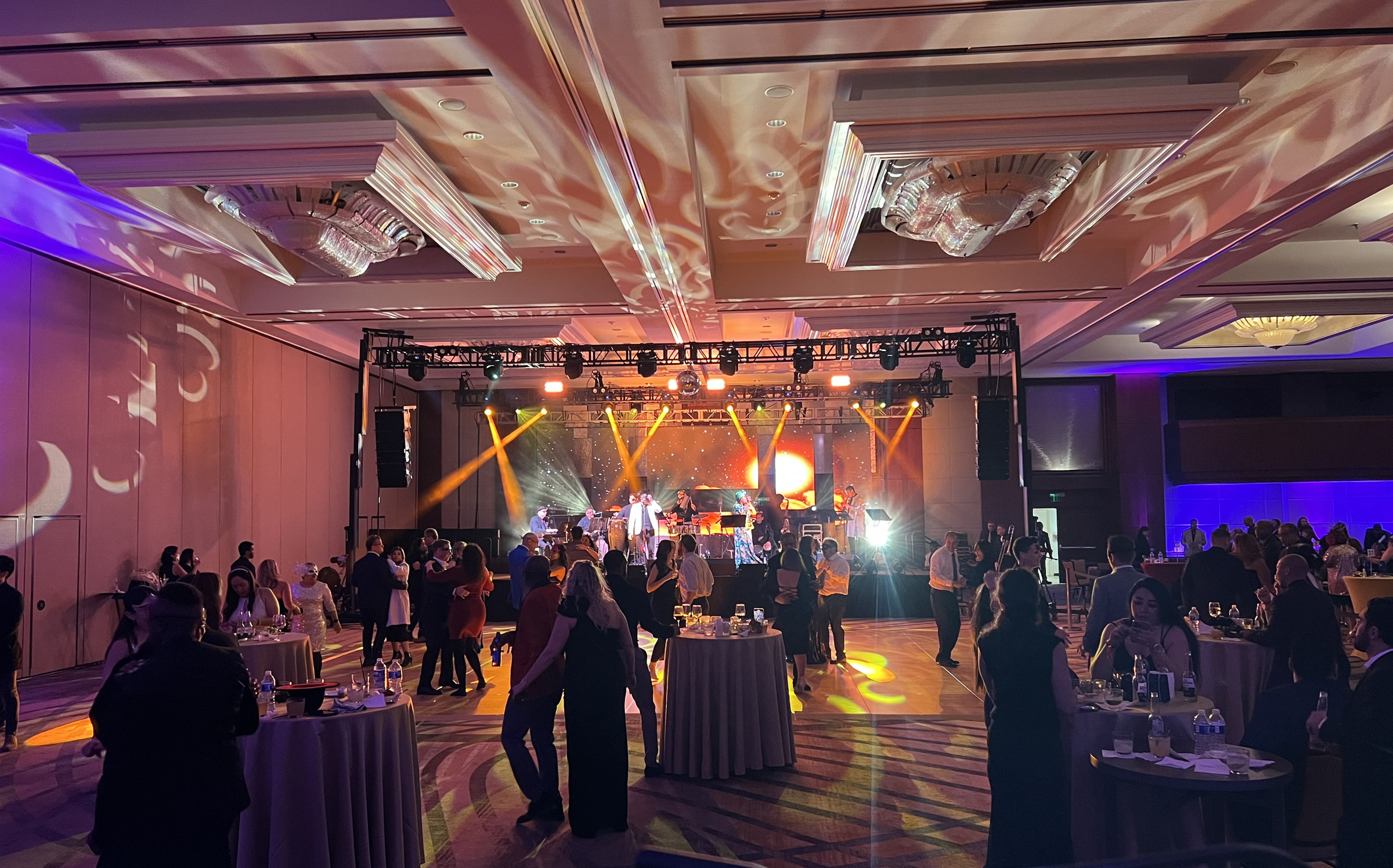 Gala reception with a live band under amber beams and purple uplighting on the drape