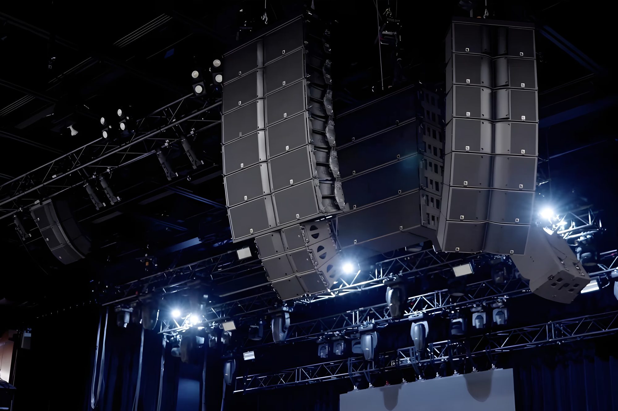 Two flown line array hangs and overhead rigging in a darkened venue