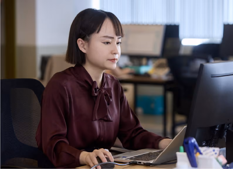 デスクトップパソコンで作業する女性社員