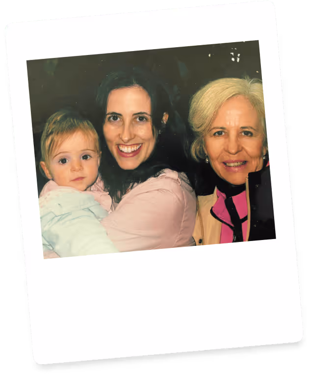 Three generations of women: a smiling woman holding a baby, with an older woman beside them.
