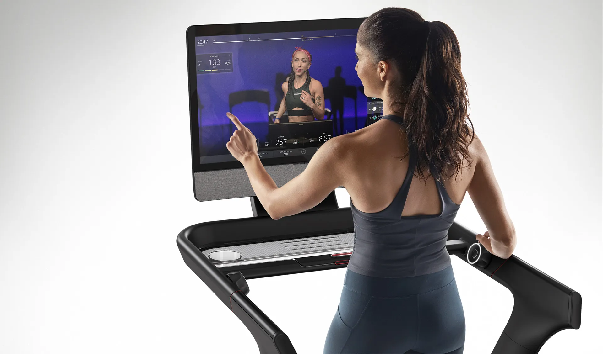 Rear view of woman on Peloton tread interacting with touch screen