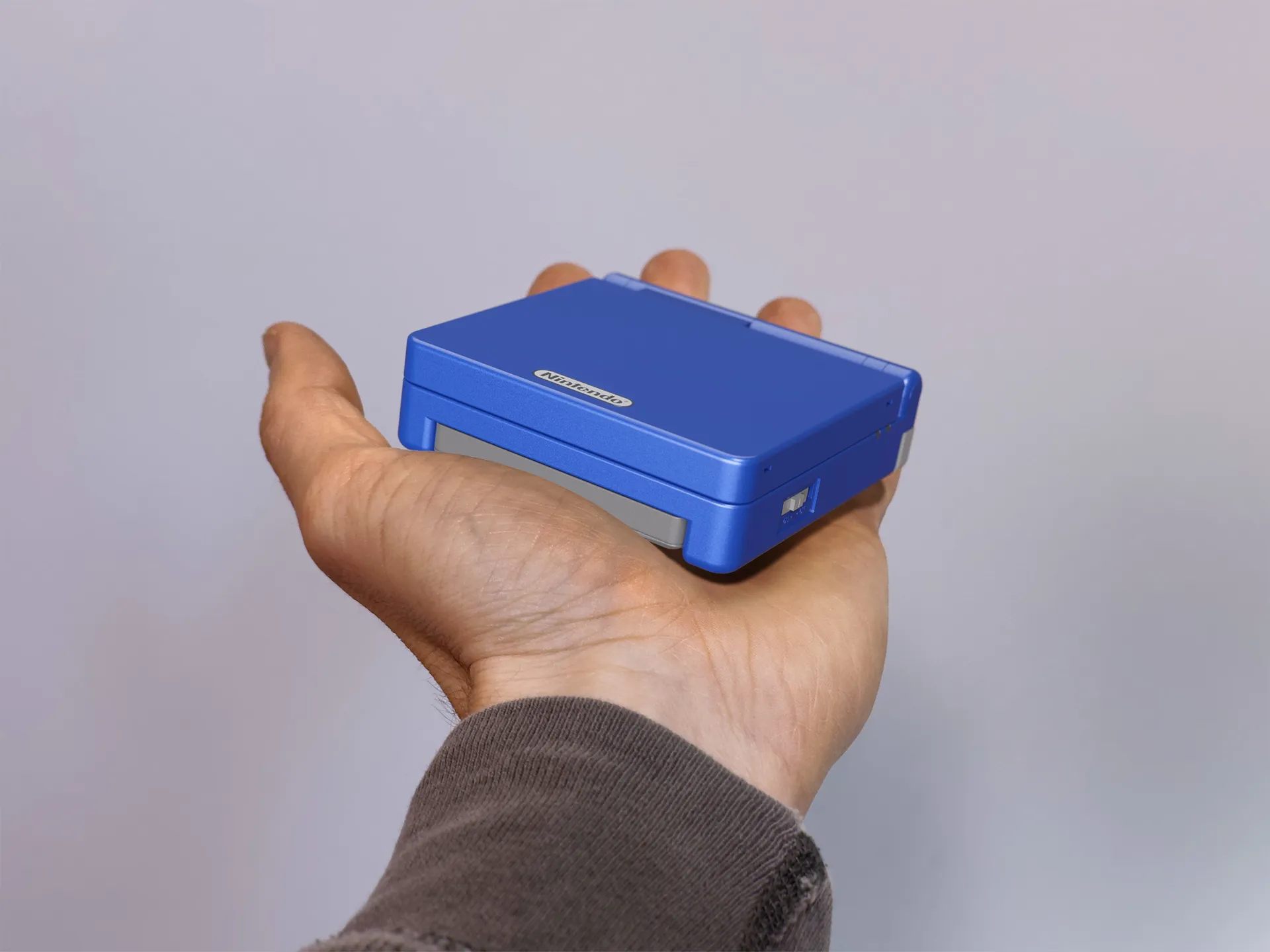 blue gameboy advance, closed position, in somebody's hand