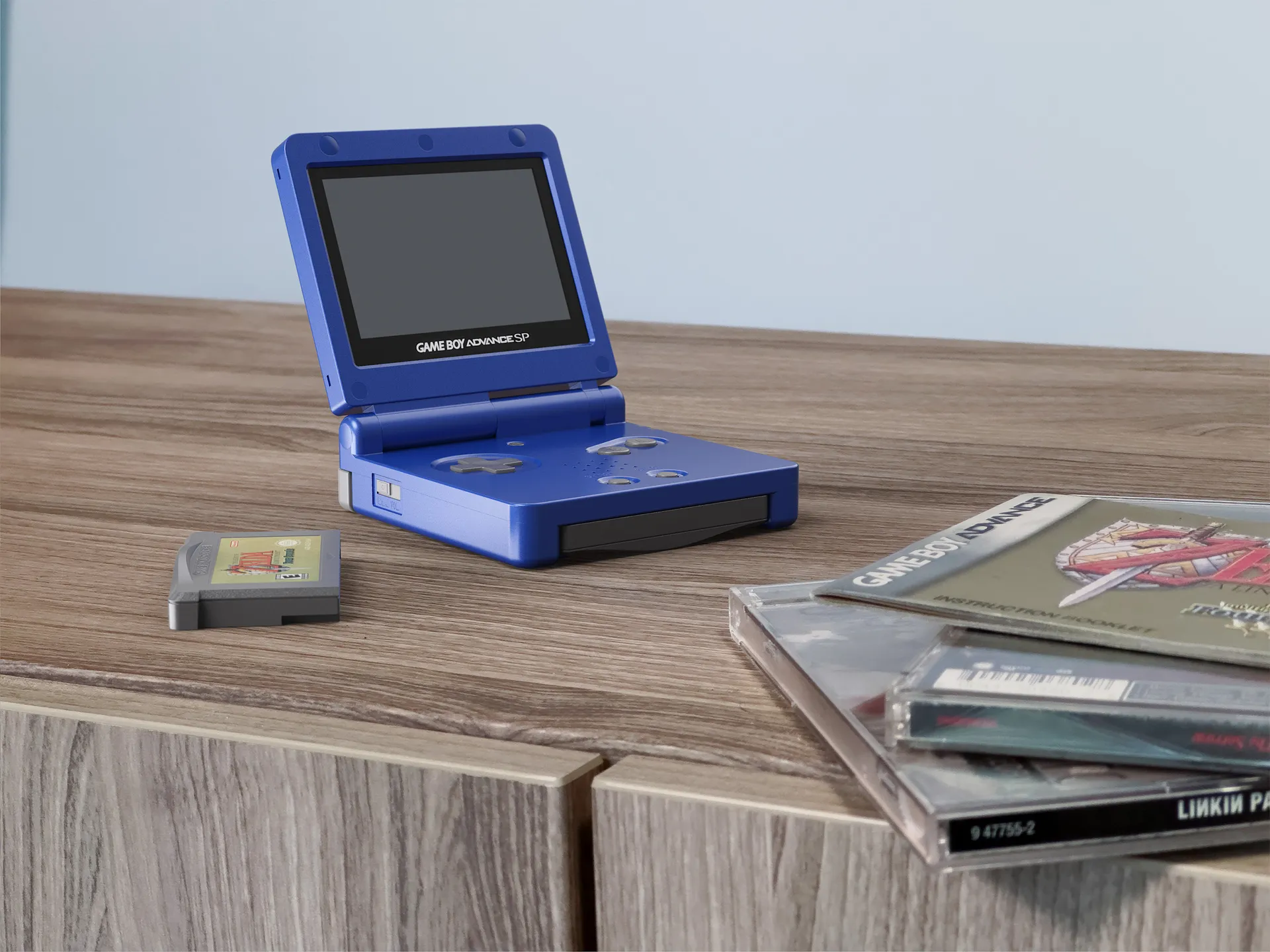 Blue Gameboy Advance open 3/4 view on media console along with game cartridge and compact discs 