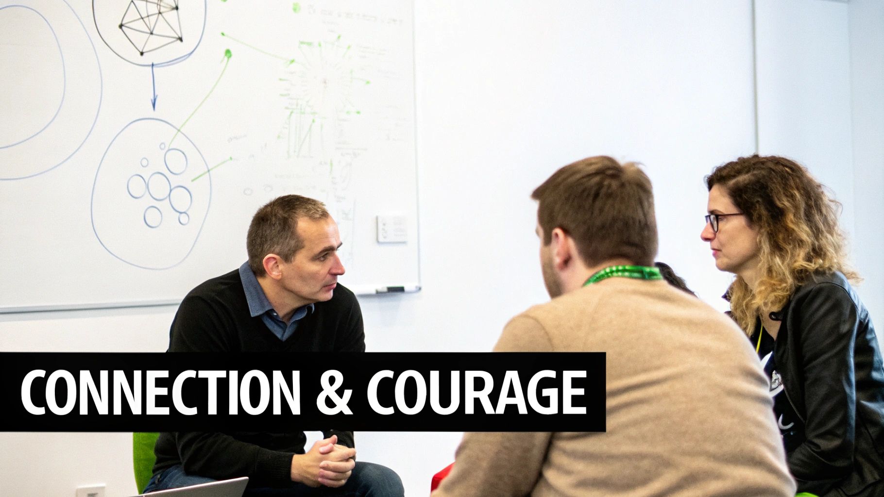 Three colleagues engage in a discussion during a meeting, with a whiteboard in the background.