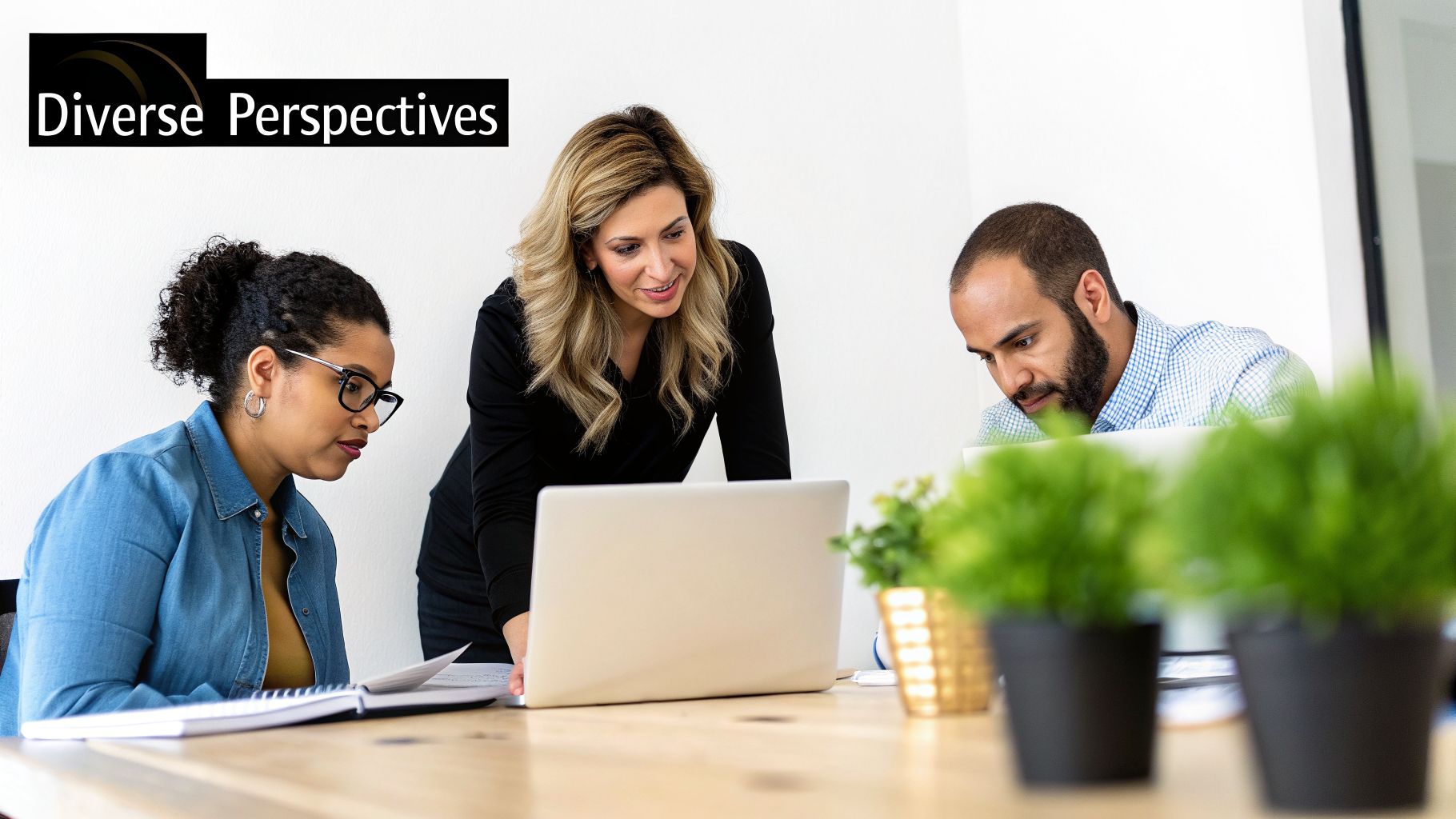 Diverse team of three professionals collaborating on laptops and documents in a modern office.
