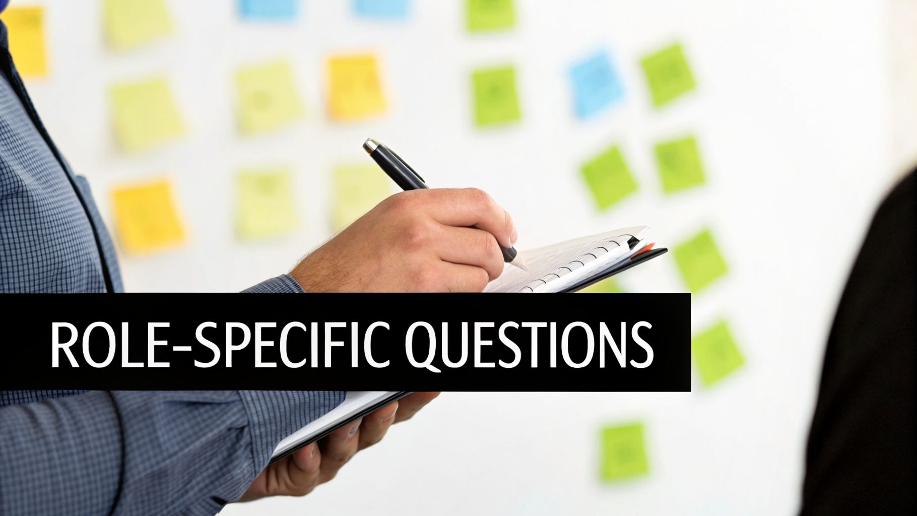A person writing 'ROLE-SPECIFIC QUESTIONS' in a notebook, with colorful sticky notes on a wall.