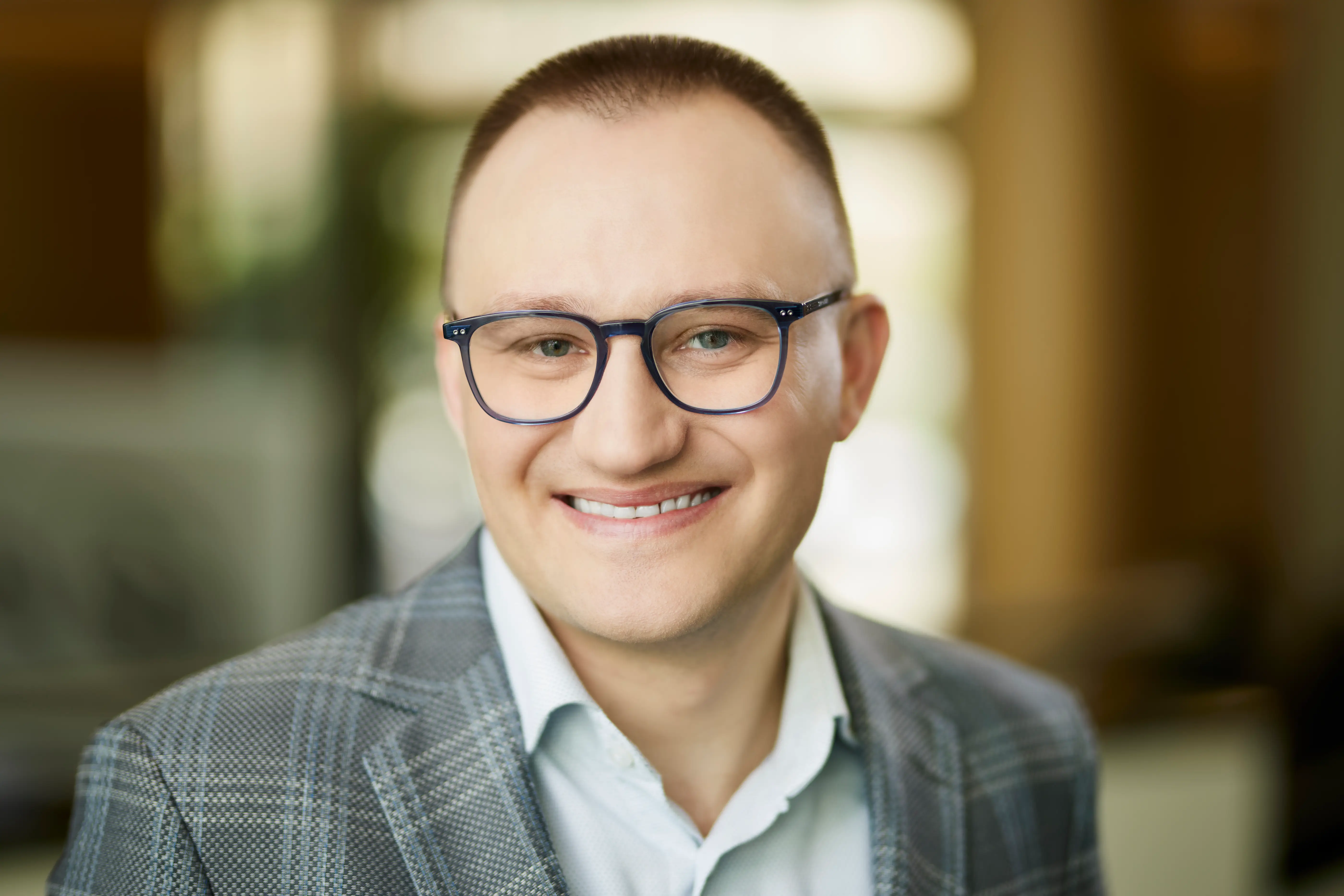 A man in a suit and glasses smiling at the camera.