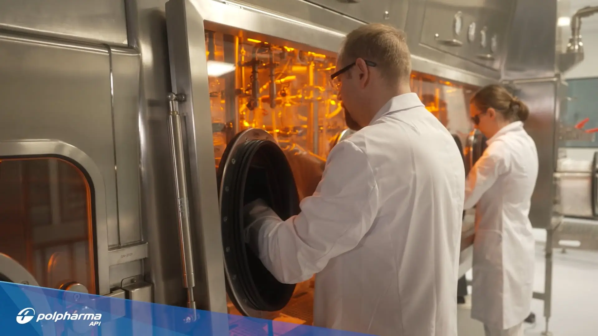 Two scientists in white lab coats working with glovebox isolators in a sterile laboratory setting.