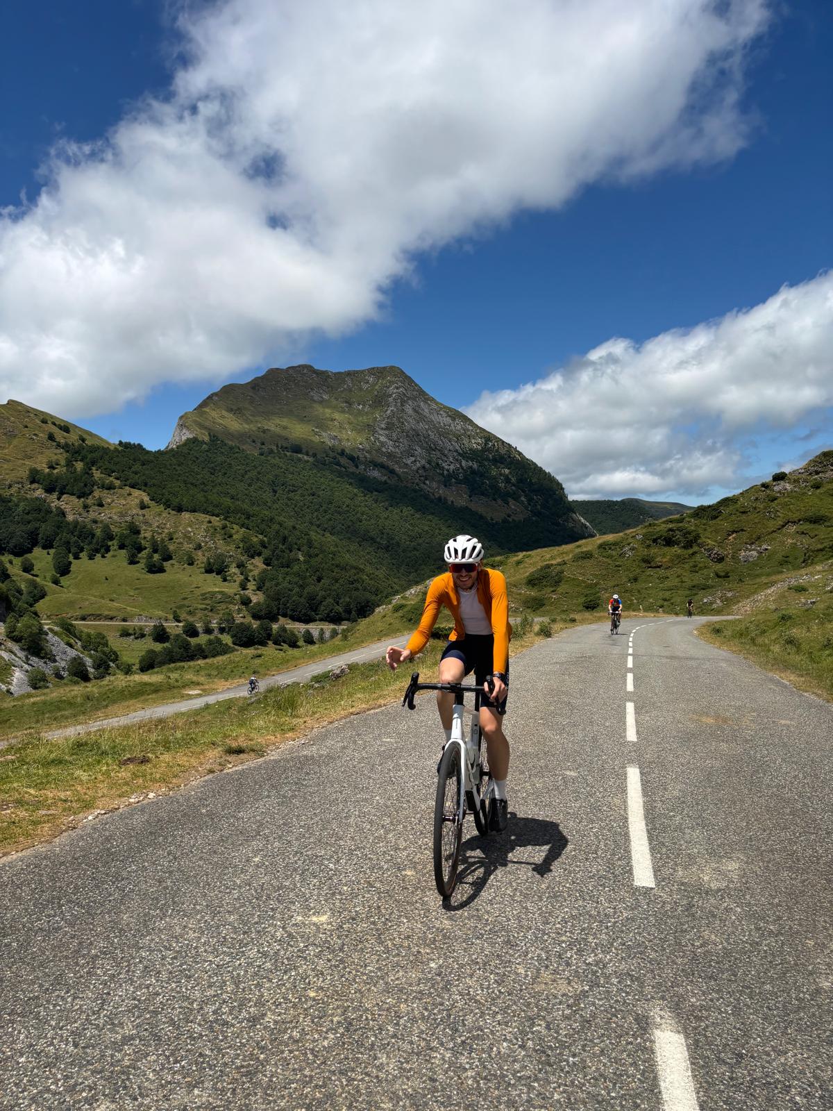 Cycliste sur route pédalant à travers les paysages montagneux sur la traversée des Pyrénées, un des plus beaux itinéraires de cyclotourisme en France. La traversée des Pyrénées de la Méditerranée à l'Atlantique est un défi incontournable pour les amateurs de vélo de route.