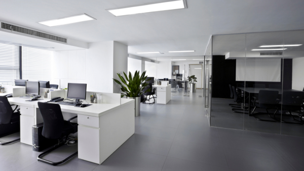 A professional cleaning service employee thoroughly sanitizes an office desk in a Miami workspace, ensuring a pristine and healthy environment for employees.
