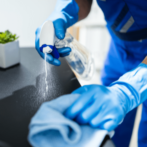 A Yeshua Cleaning employee spraying and wiping down an office table in a Miami office, using hospital-grade disinfectants to ensure a hygienic and safe workspace.