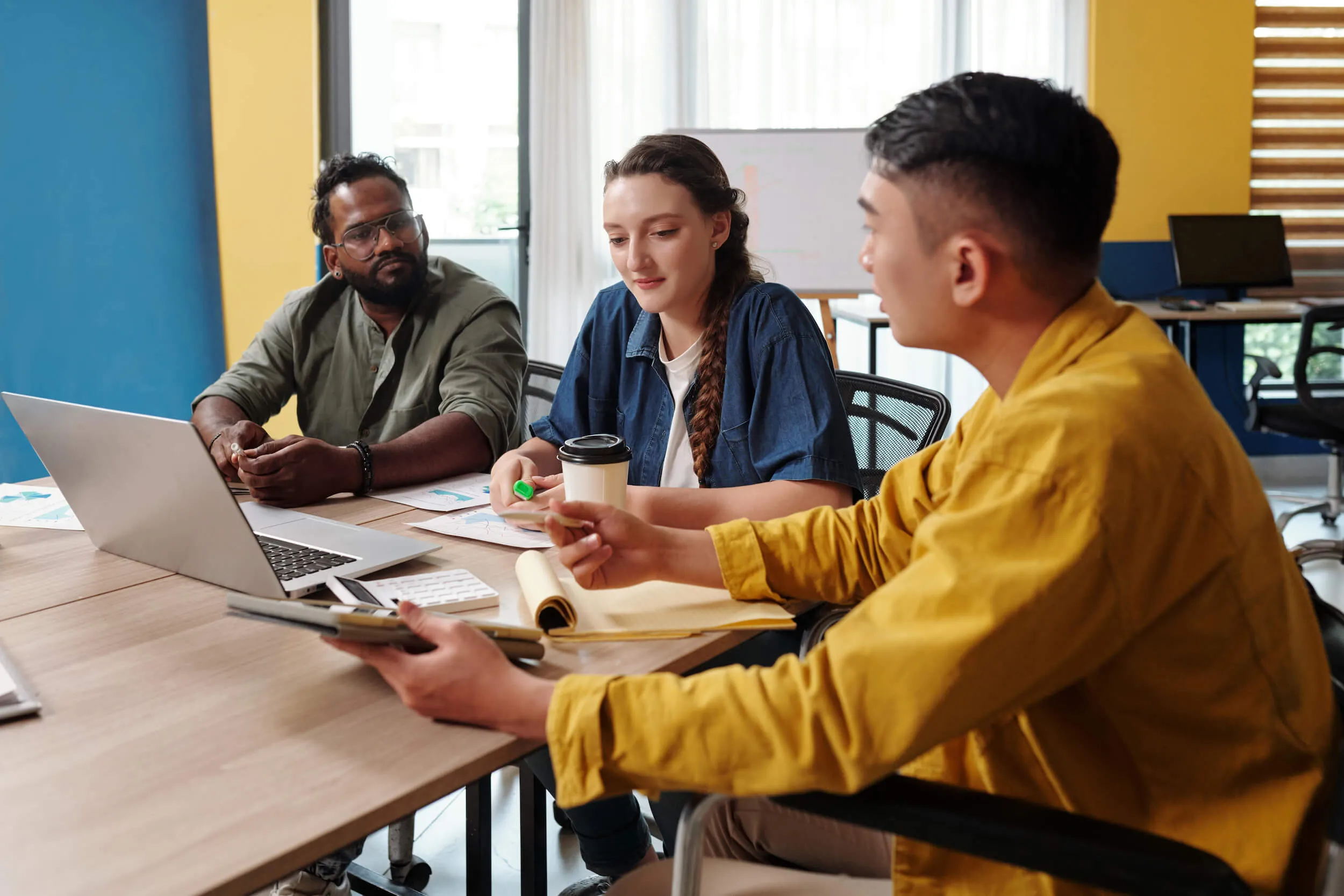 group of people talking at table with notepads and calculators