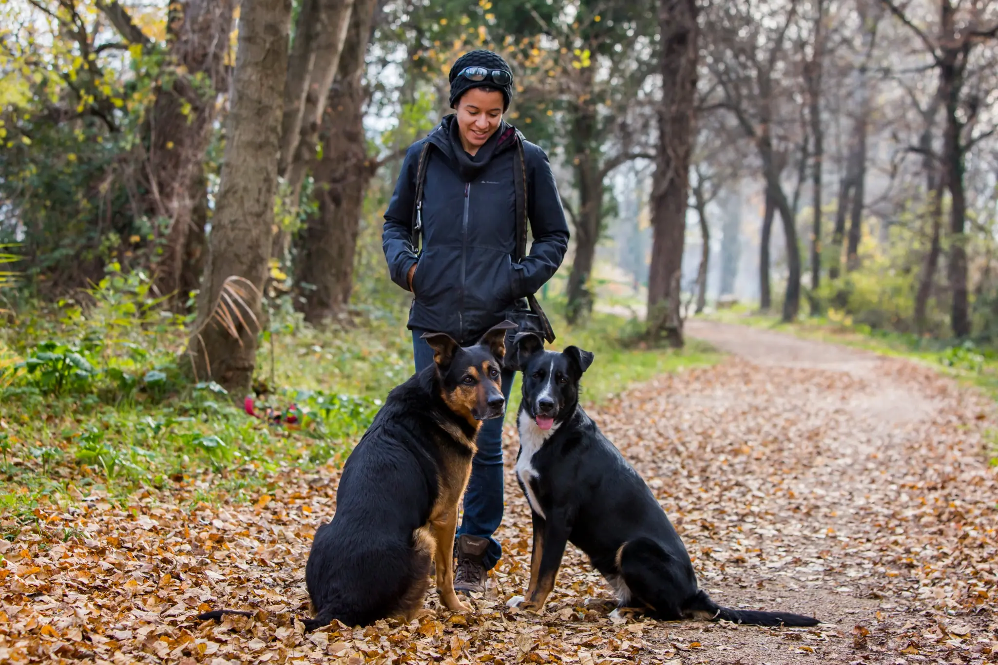 Mélissa Ndongo debout dans la forête avec son chien Shogun et sa chienne Maiko.